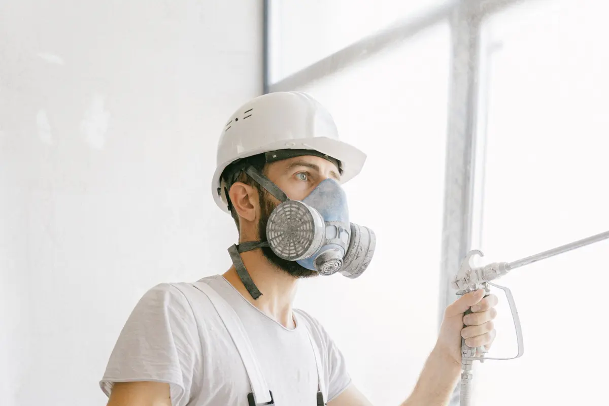 Professional painter in a respirator using an airless spray gun