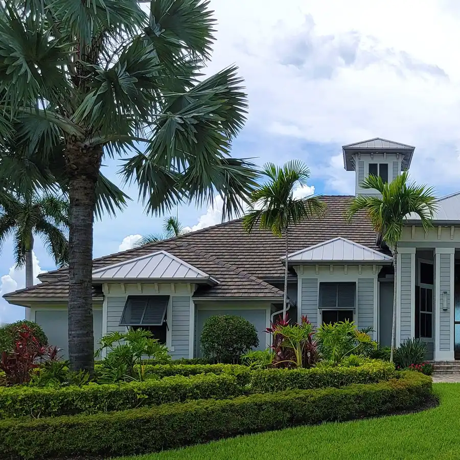 Single-story Florida home with a metal roof, palm trees and a manicured front lawn