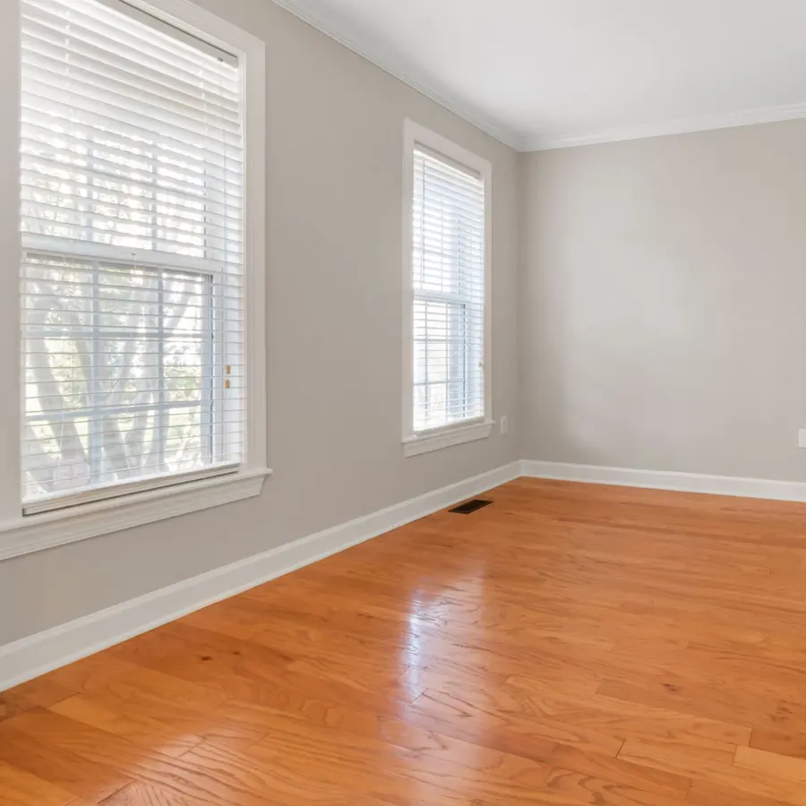 Empty room with freshly painted light gray walls, white trim and wood floors