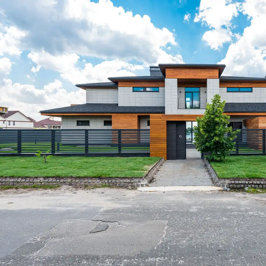 Modern two-story home with a gray and wood facade in a Florida neighborhood