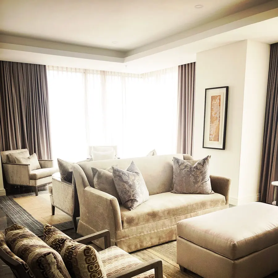 Cozy sitting room with neutral walls, soft sofas and tall windows