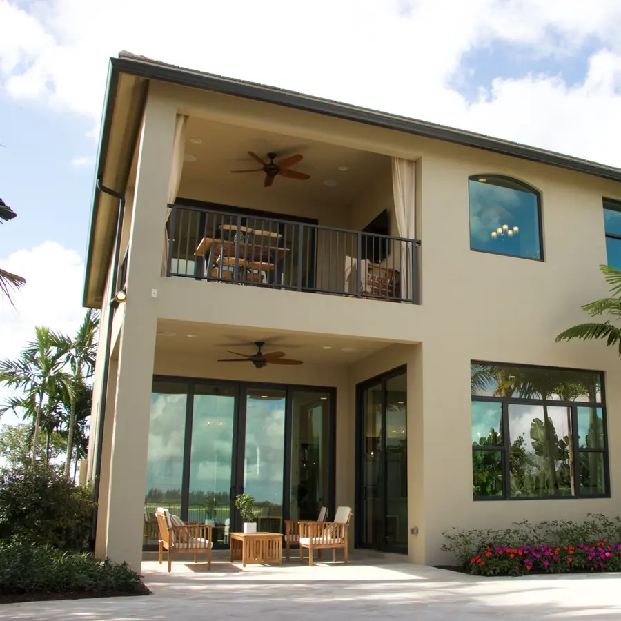 Two-story stucco home with palm trees and a covered balcony