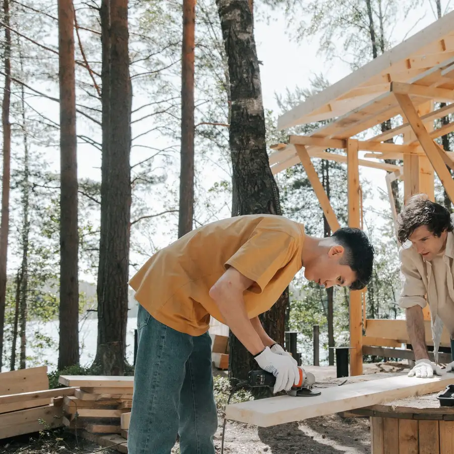 Two carpenters in work gloves building a wooden outdoor structure