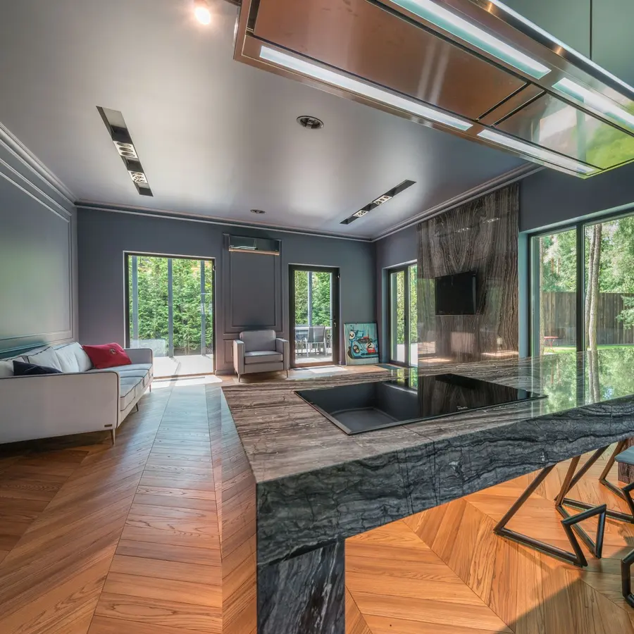 Renovated open living space with wood floors, a stone kitchen island and large windows